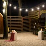 Garden with a wooden gazebo with lights, candles at night at a wedding
