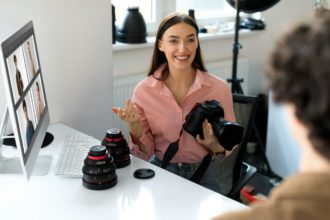 The art of feedback. Young photographer lady showing results of photoshoot to guy, discussing photos